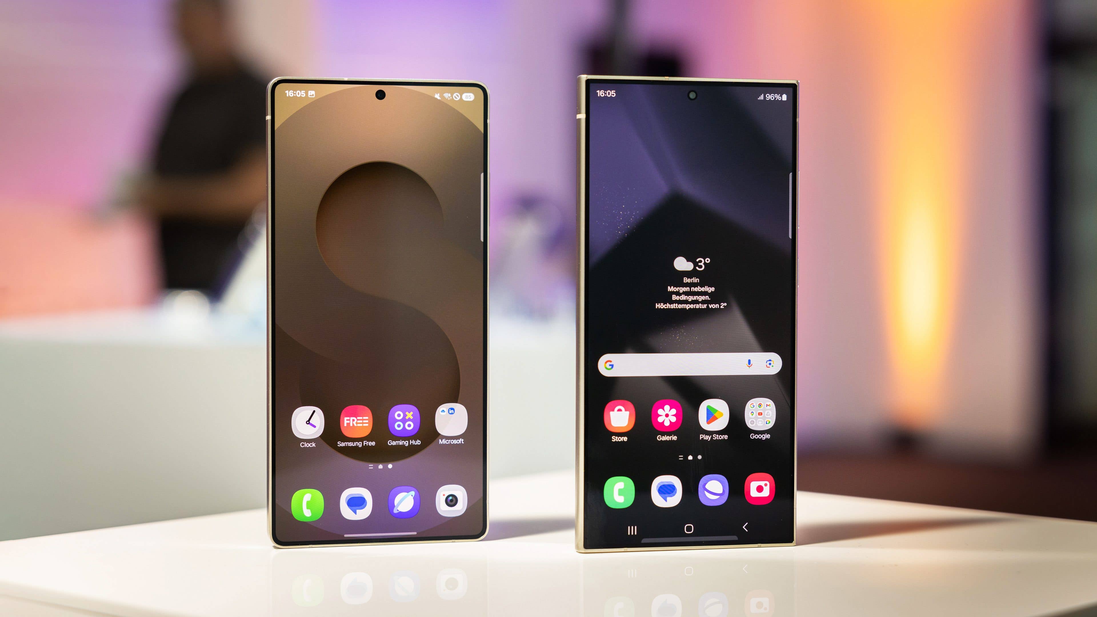 Two Samsung Galaxy S25 smartphones displayed on a table with vibrant backgrounds.