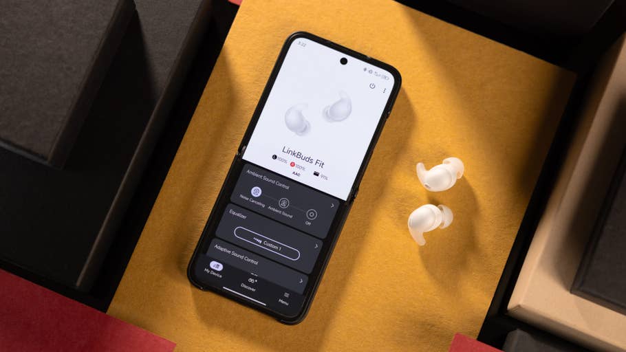 Un smartphone affichant lu0027application LinkBuds Fit à côté des écouteurs sur un fond coloré.