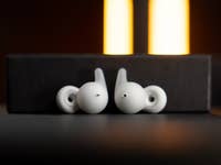 Buds Sony Link blancs reposant sur une boîte noire avec un éclairage doux en arrière-plan.