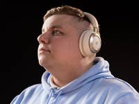 Une personne portant des écouteurs Anker Soundcore Space One, regardant pensivement vers le haut sur fond noir.