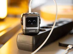 Le chargeur Ugreen Nexode Robot GaN branché sur une multiprise en connecté à un iPhone posé à côté