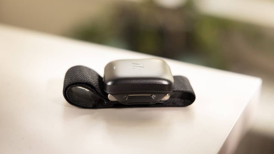 Un appareil noir portable au poignet avec une bande, posé sur une surface blanche.