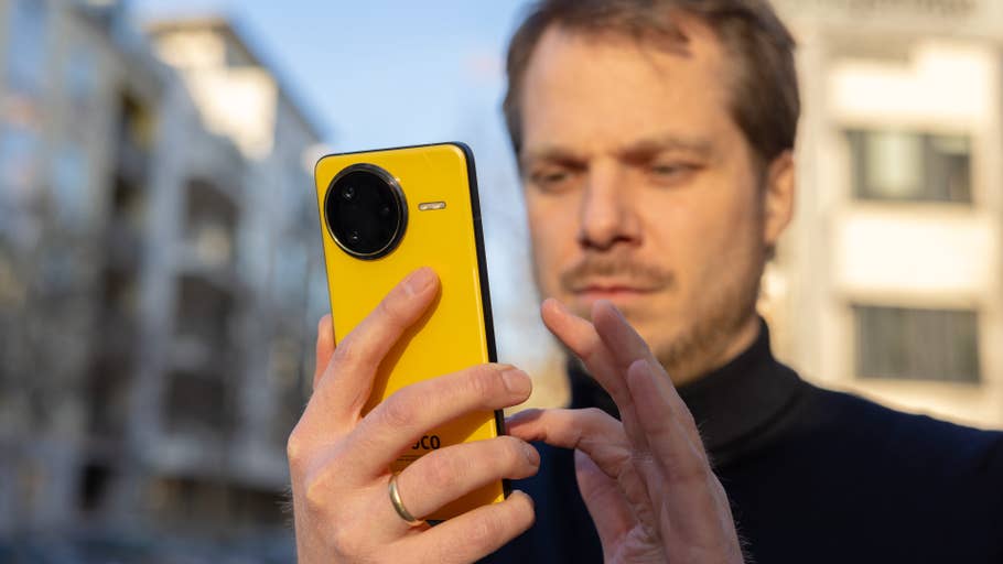 Un homme tenant un smartphone Poco F7 Ultra jaune à lu0027extérieur.