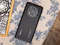 Smartphone Xiaomi Redmi Note 14 Pro 5G noir sur une nappe à motif floral.