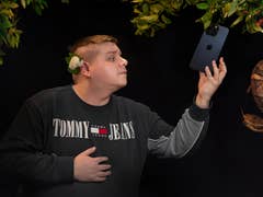 Le testeur Antoine qui prétend cueillir l'iPhone 15 Pro Max d'un arbre, comme une Pomme, avec un serpent enroulé autour de l'arbre en référence au mythe d'Adam et Eve