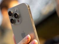 Gros plan d'un iPhone 16 Pro tenu à la main, mettant en valeur sa caméra et ses boutons.