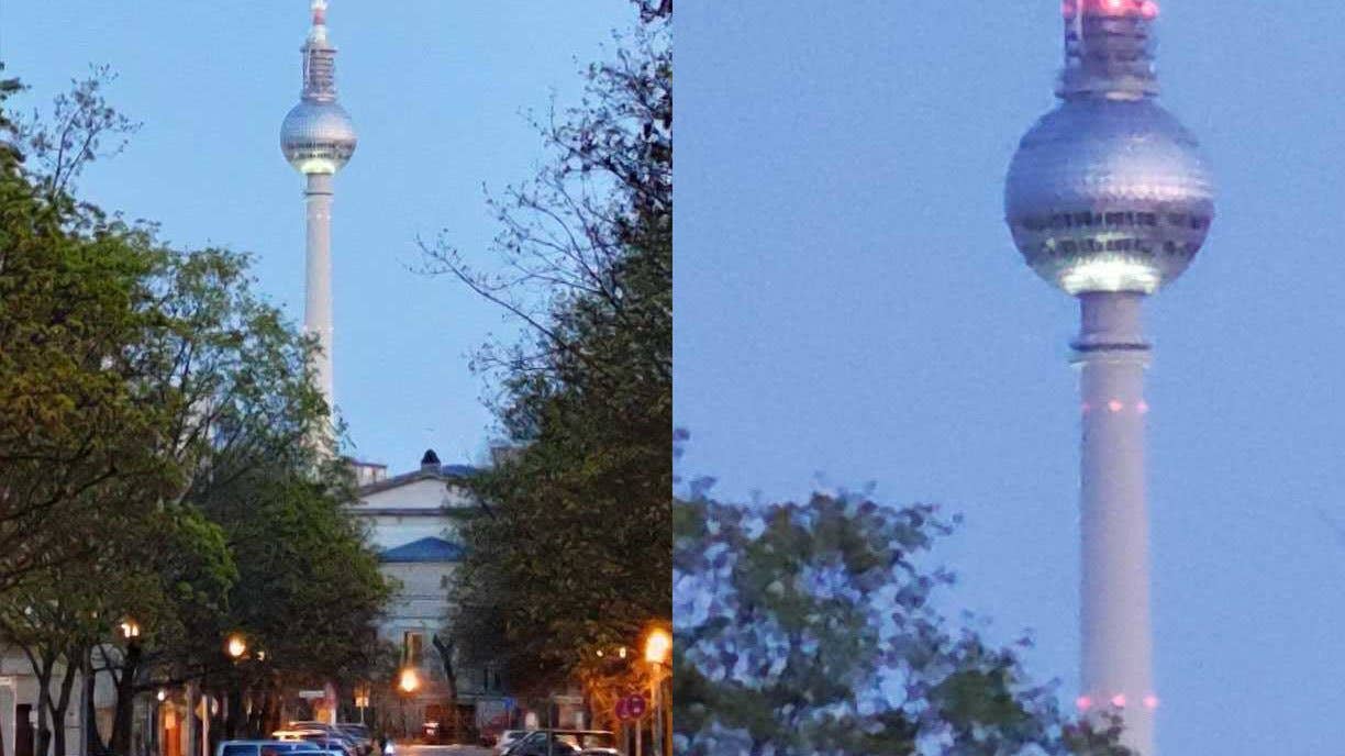 Une grande tour avec un sommet sphérique illuminé la nuit, entourée d'arbres et de lampadaires.