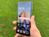 Une personne tenant le smartphone Oppo Find X8 Pro à l'extérieur avec un fond d'écran de montagne.