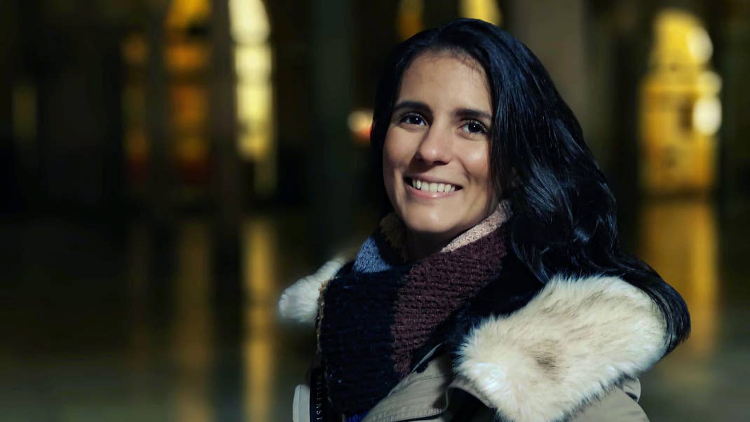 Une femme souriante en photographie nocturne, avec un éclairage doux et un fond flou.