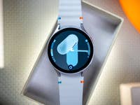Une Samsung Galaxy Watch 7 présentée dans une boîte avec un bracelet bleu et blanc affichant un cadran numérique.