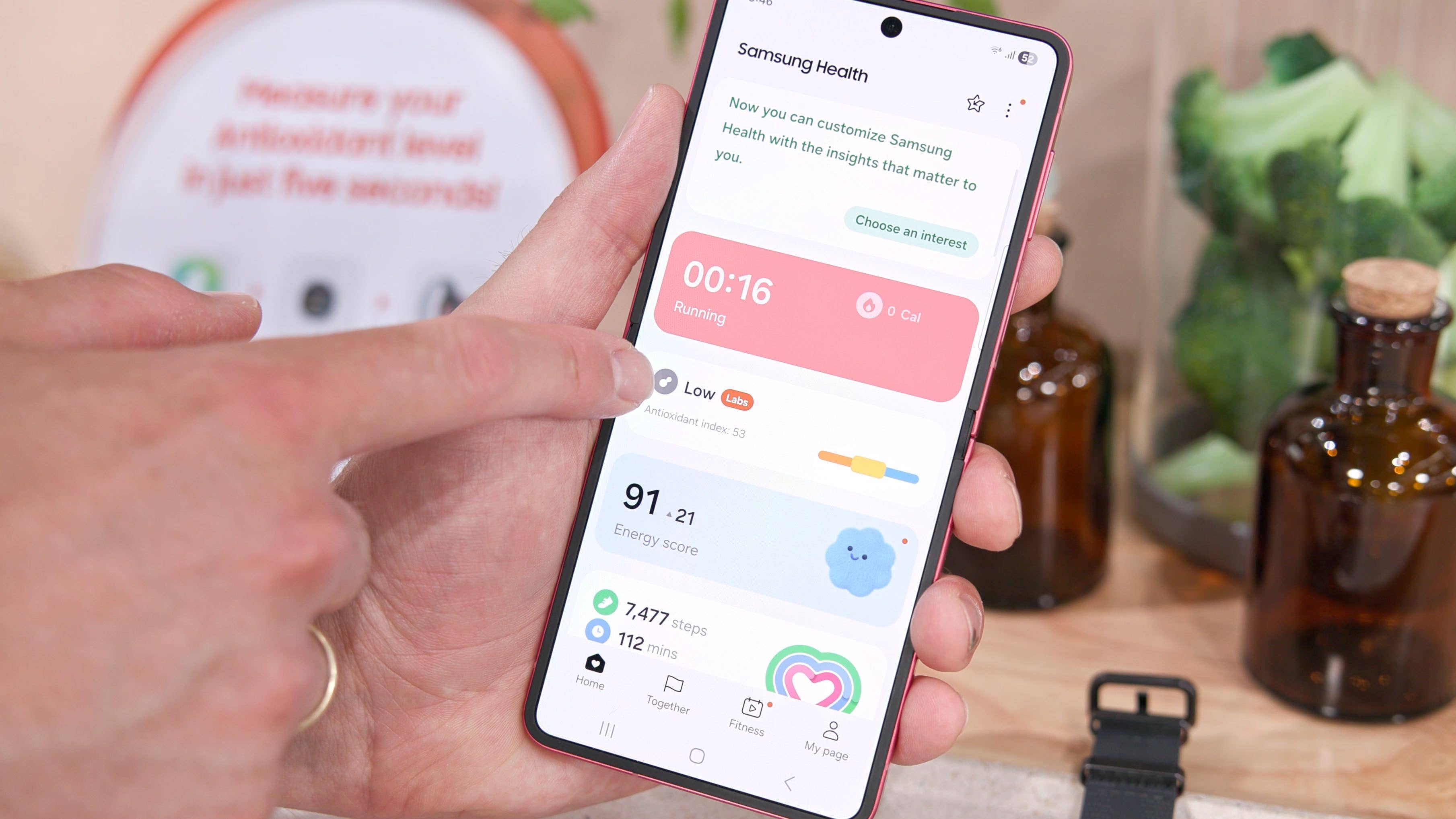 Une personne interagit avec l'application Samsung Health sur un smartphone, affichant des statistiques de course et le niveau d'antioxydants.