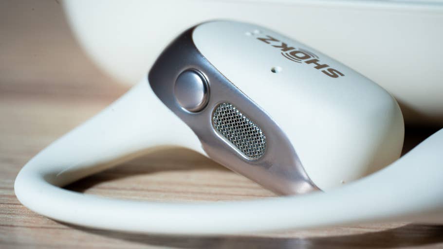 Gros plan des écouteurs sans fil Shokz OpenFit 2 sur une surface en bois.