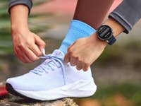 Amazfit Active 3 Premium au poignet d'une femme en train de lacer sa chaussure de course.