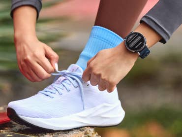 Amazfit Active 3 Premium au poignet d'une femme en train de lacer sa chaussure de course.