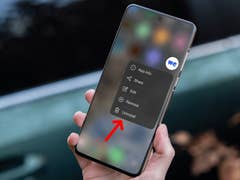 Une main tenant un smartphone affichant un menu avec des options, y compris 'Désinstaller' en surbrillance.