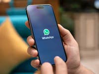 Une main tenant un smartphone affichant le logo WhatsApp à l'écran.