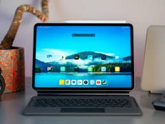 Un Xiaomi Pad 7 sur un bureau avec un clavier, un appareil photo et une plante en pot en arrière-plan.