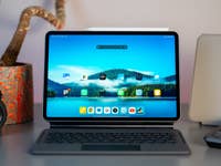 Un Xiaomi Pad 7 sur un bureau avec un clavier, un appareil photo et une plante en pot en arrière-plan.