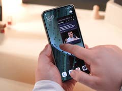 Le Xiaomi 14 Ultra tenu dans une main avec un doigt touchant son écran pour ouvrir une application en mode fenêtré