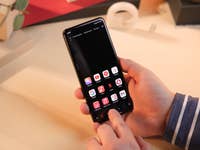 Un smartphone Xiaomi tenu dans une main avec le tiroir d'applications affiché sur son écran allumé